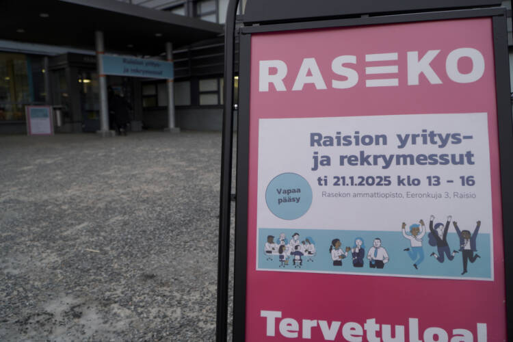 Raision yritys- ja rekrymessujen juliste a-telineessä koulurakennuksen edessä.